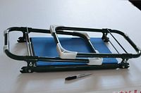 Image showing folded garden kneeler with green metal frame and blue padded cushion next to a marker for scale