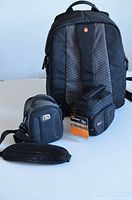 Front view of Manfrotto backpack standing behind two small camera bags on a light surface