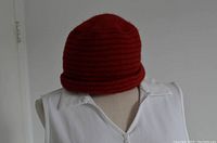 Front view of red knit hat displayed on mannequin torso wearing white shirt.