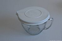 Glass measuring cup with white lid on, showing spout and handle.