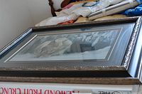 Overall framed print showing the sizeable frame on a bed with some household items nearby.