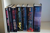 Photo of 7 Stephen King hardcover books including The Dark Tower series and Under the Dome arranged upright.