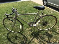Full side view of the silver 1979 Schwinn Varsity bicycle showing drop handlebars, black saddle, and thin tires on grassy lawn.