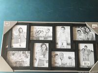 Photo of one black collage picture frame designed to hold seven photos in different sizes, showing Melamco branding and barcode sticker on corner.