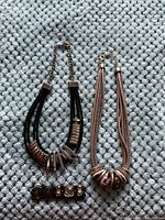Photograph of two necklaces and one bracelet on a textured grey surface