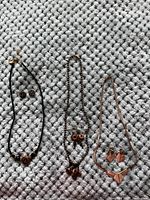 Photo of three costume jewelry necklaces and their matching earrings placed on a textured surface