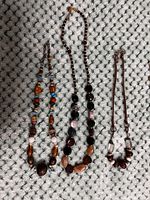 Photo of three costume jewelry beaded necklaces laid flat on a textured fabric background. Clear view of beads, chain links, and clasp types.