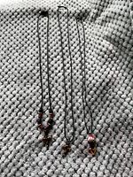 Three necklaces laid out on textured fabric background, showing chains and pendants clearly.