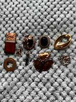 Seven assorted vintage costume jewelry pins on a light gray textured fabric.