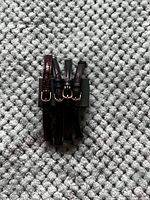 Four watch bands stacked vertically on grey carpet, varying dark colors, gold-tone buckles