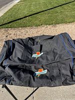 Two black nylon Gatorade duffel gym bags with blue piping and colorful Gatorade logos, displayed outdoors on a chair and concrete surface.