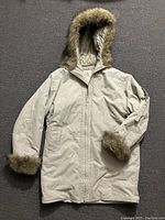 Beige hooded women's coat with quilted interior and faux fur trim on hood and cuffs