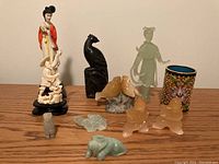 Group of carved figurines and cup arranged together: porcelain woman, jade female, bone fisherman, jade minis, soapstone seals, enamel cup