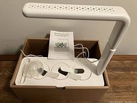 White SmartGarden 3 base with 3 plant pod slots, adjustable grow light arm, and planting tools inside box