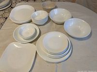 Overview of the assortment including stacks of plates and bowls, and a square serving dish