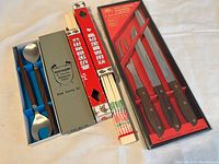 Image of stainless steel salad serving spoon set, multiple pairs of chopsticks in original packaging, and 4-piece carving knife set in red box.