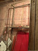 Aluminum shelving frame partially assembled with vertical slotted supports in unfinished basement wall setting.