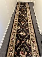 Full length view of the long hallway runner rug showing the floral pattern and border design on a dark field.