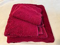 Set of red towels: two bath-sized towels and one smaller towel on top