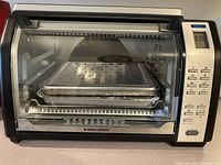 Front view of Black & Decker toaster convection oven with trays inside and digital control panel on right side.