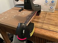 Close-up of the front section of the paper trimmer showing the black plastic laser cutter mechanism and warning label.