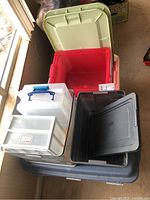 Large plastic storage bins stacked, various colors including red, blue, green, and gray lids
