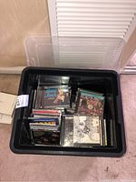 Large black bin filled with assorted music CDs including visible Beatles and Harry James albums