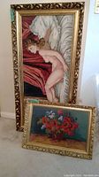 Two framed cross stitch artworks leaning against a wall, showing sizes and frames