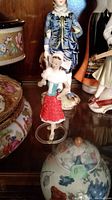 View of two porcelain figurines on shelf showing fine detail, woman in red skirt and man in blue outfit