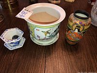 Photo showing all three items: two plant pots (one medium with birds and bamboo design, one small blue and white hexagonal) and one East Asian style vase with detailed painted woman and floral patterns.