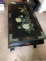 Rectangular lacquered table with floral and bird artwork on top and decorative base.