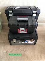 Four stacked empty tool boxes. Top two are Husky brands, bottom one Maximum brand with label visible. All black with metal latches.