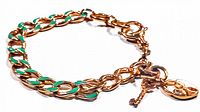 Close-up of gold-tone chain link bracelet with green enamel inlay and toggle clasp, showing signed Fossil charm