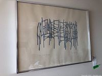 Full view of framed abstract print in silver metal frame hung on wall