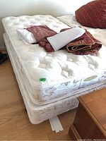 White Sears single box spring and bed frame with patterned bedding on top