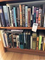 Two wooden shelves filled with assorted books of various heights, colors and authors, some grouped by Margaret Atwood and Carol Shields.