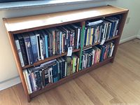 Front view of wooden bookshelf filled with books to illustrate size and style, books not included in lot