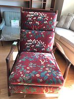 Front view of teak armchair with red floral tapestry cushions.