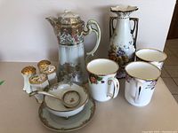 Full china lot including coffee pot, mugs, serving bowl, salt and pepper shakers, and decorative vase arranged on table