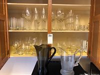 Two shelves of assorted clear glassware, plus two pitchers in front