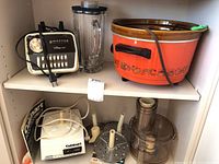 White Cuisinart mixer with plastic attachments and a large orange Rival crockpot without the lid