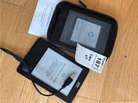 Two Kobo eReaders shown together, one in protective case with charger cable and manual, other standalone with charger cable.
