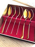 Six Yuban Gold spoons inside a display box with red felt lining.