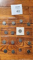16 Canadian nickels arranged on wooden surface with auction card number 40 visible