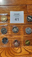Eight different Canadian medallions arranged on wooden floor with auction lot card