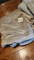Weighted blanket with beige quilted removable cover folded on wooden floor with attached label visible.