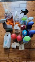 Collection of cleaning sprays, Method wood floor cleaner refill and daily cleaner, several aerosol air fresheners in red, green, blue, white, white and blue Air Wick dispenser, Febreze plug-in, and other bottles grouped on wood floor.