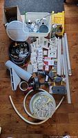 Overview photo showing all hardware, plumbing parts, shower heads, electrical parts, and other accessories arranged neatly on the floor including two containers.