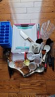 Kitchen items including cutting boards, pitcher, ice trays, cooking utensils, measuring cups, Henckels peeler shown against wood floor.