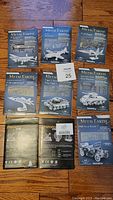 Set of 9 Metal Earth and Piececool 3D laser-cut metal model kits laid out on hardwood floor, showing front and back of packaging. Includes various aircraft, military tanks, and 1908 Ford Model T car.